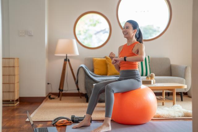 Woman_sitting_on_exercise_ball_working_out_at_home_or_studio.jpg