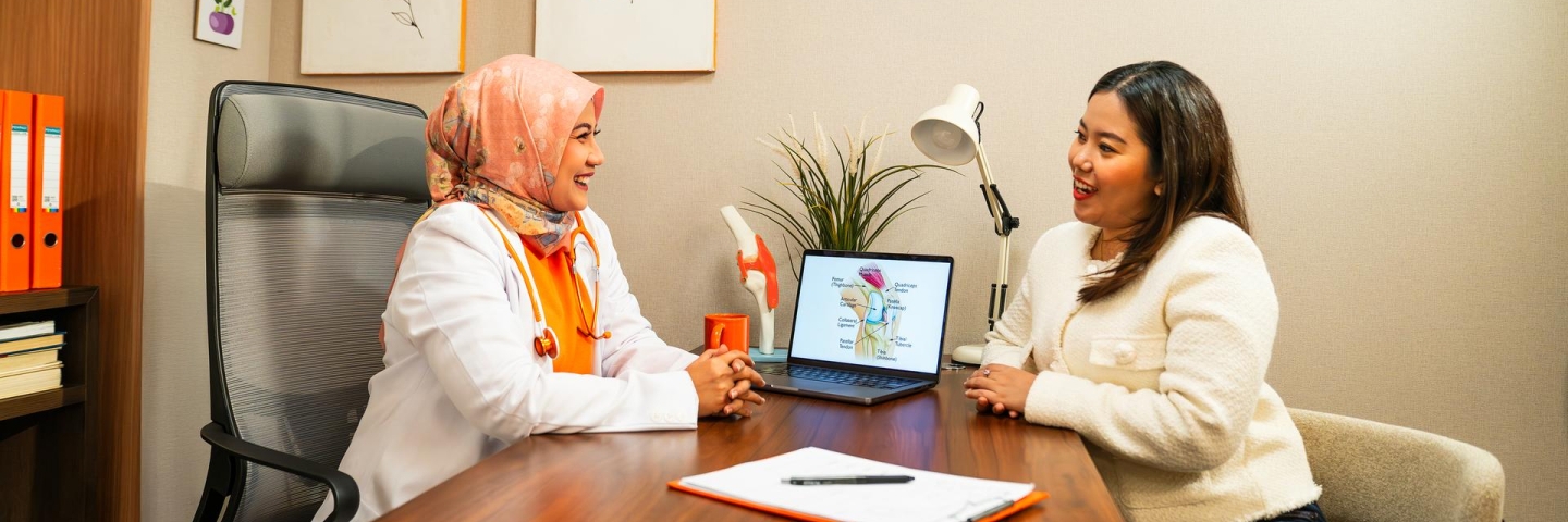 Seorang wanita sedang berkonsultasi dengan seorang dokter spesialis di sebuah klinik.