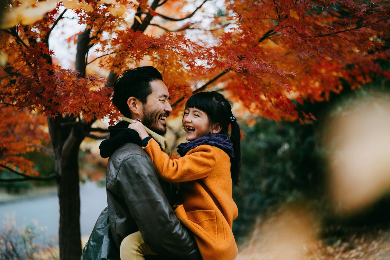 Father_holding_daughter_under_autumn_leaves.jpg