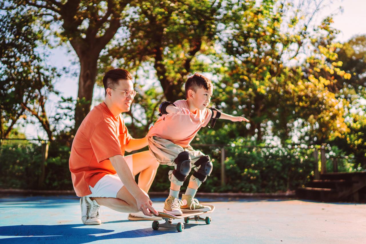 _Dad_teaching_son_skateboarding_at_park.jpg